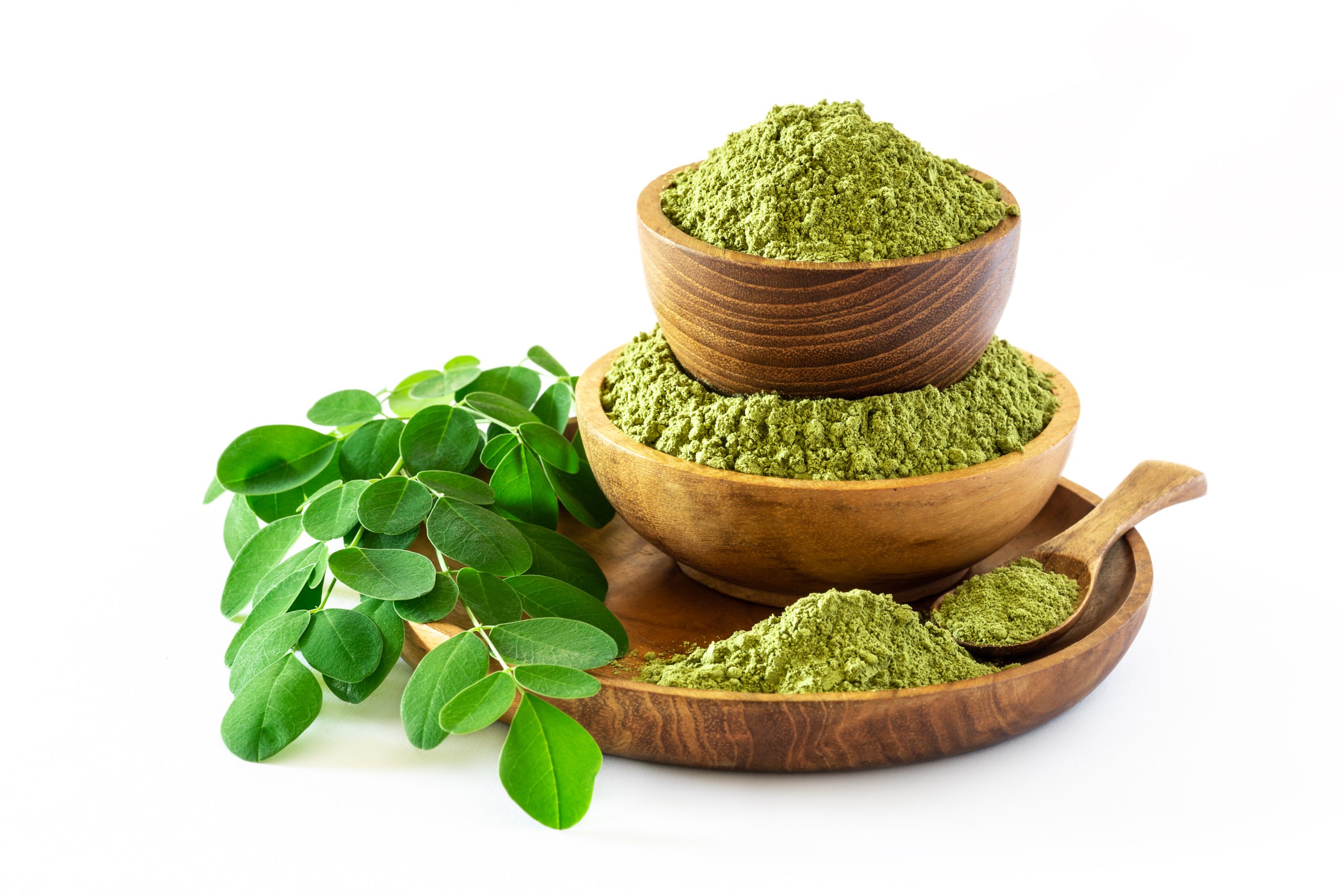 Moringa powder (Moringa Oleifera) in wooden bowl with original fresh Moringa leaves isolated on white background. Healthy product, superfood, vitamin.